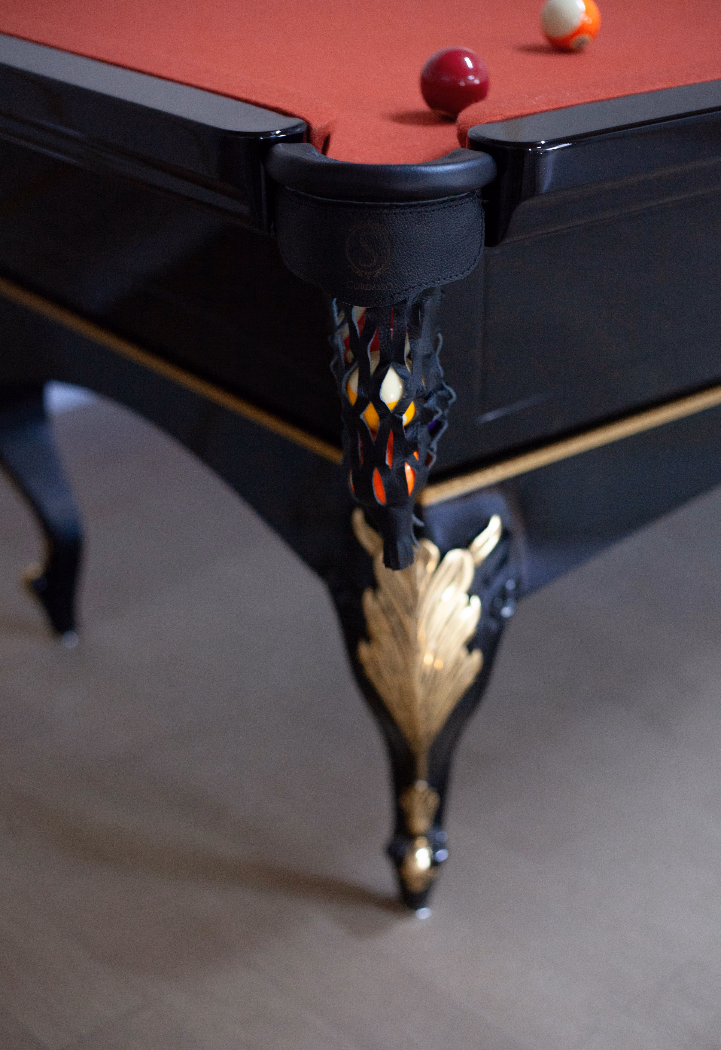 Detalhe da caçapa de couro e pé entalhado em dourado.