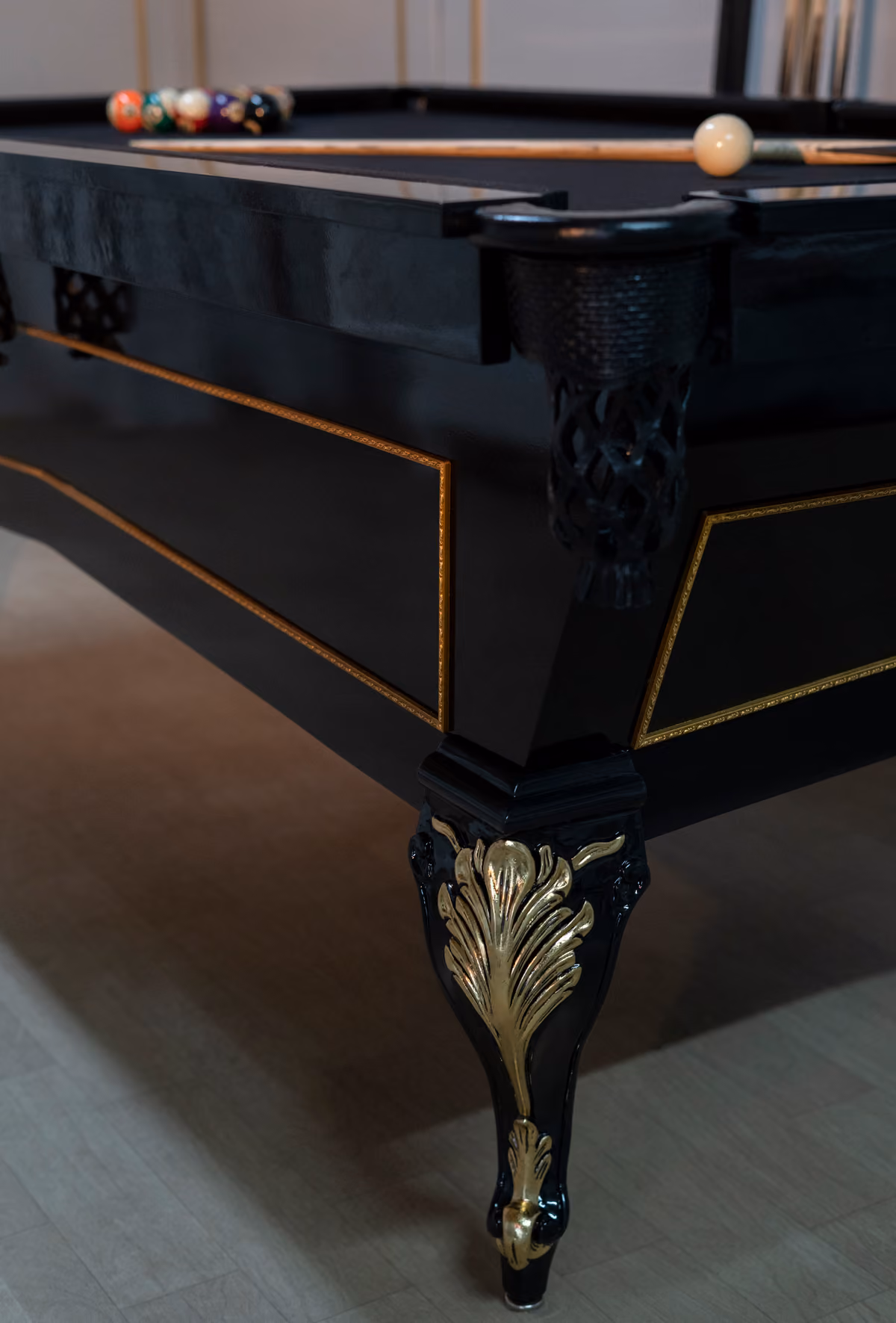 Detalhe do pé ornamentado em ouro e caçapa de bilhar preta.